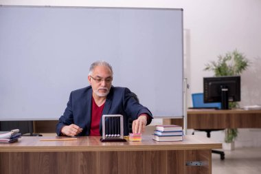 Sınıfta oturan eski bir fizikçi öğretmen.