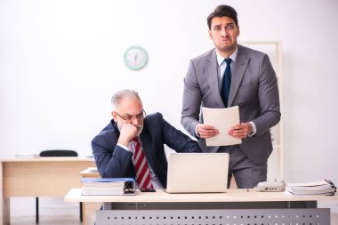 Eski patron ve genç erkek çalışan ofiste çalışıyor.