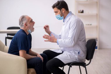 Yaşlı erkek hasta genç doktor otorhinolaryngologis 'i ziyaret ediyor.