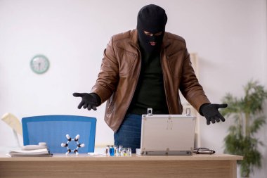 Kar maskeli genç adam laboratuvardan aşı çalıyor.