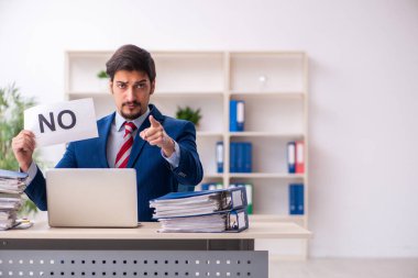 Ofisteki aşırı işten memnun olmayan genç bir erkek işçi.