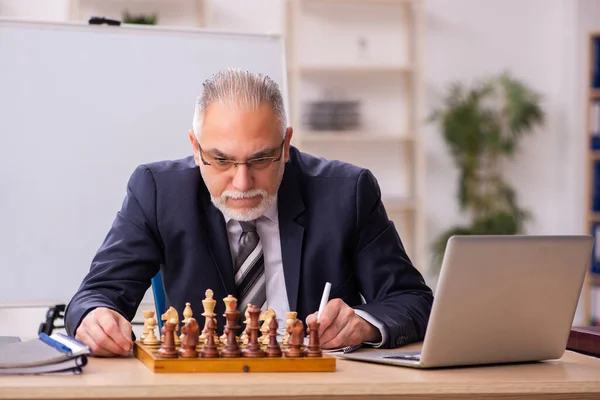 Old male employee playing chess at workplace — Stock Photo, Image