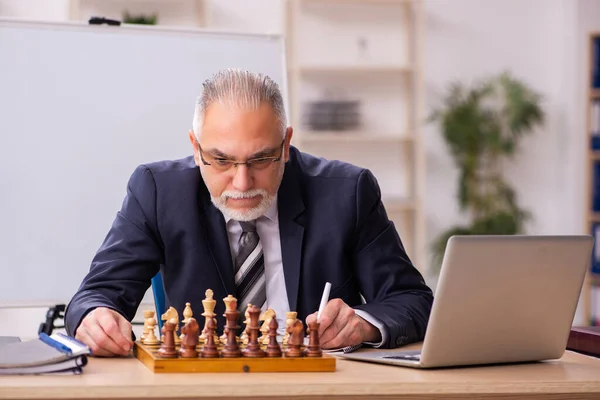 Viejo empleado jugando ajedrez en el lugar de trabajo — Foto de Stock