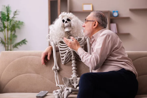 Old man sitting on the sofa with the female skeleton — Stock Photo, Image