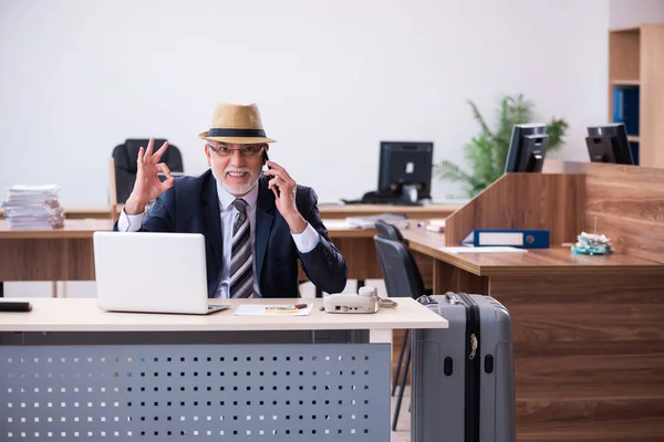 Old male employee preparing for travel in the office — Stock Photo, Image