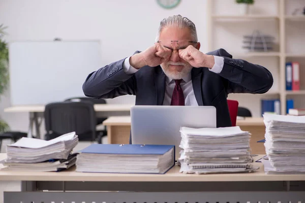 Empleado de edad avanzada y demasiado trabajo en el lugar de trabajo — Foto de Stock