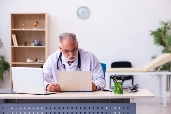 Gammal manlig läkare som arbetar på kliniken — Stockfoto