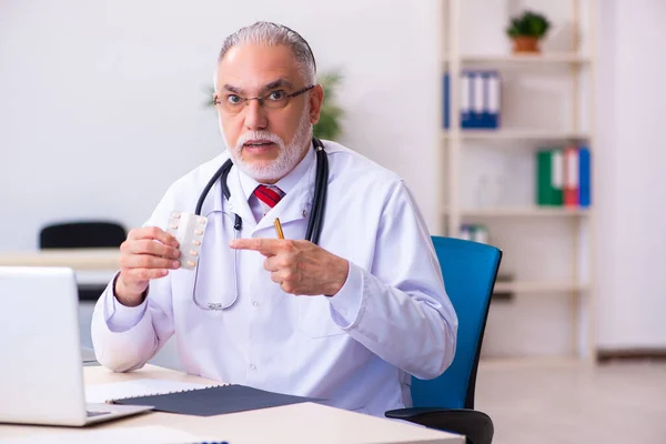 Viejo médico masculino sosteniendo píldoras —  Fotos de Stock