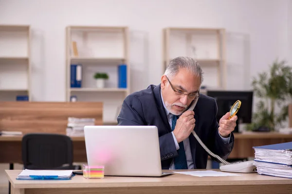 Velho empregado auditor segurando loupe no local de trabalho — Fotografia de Stock