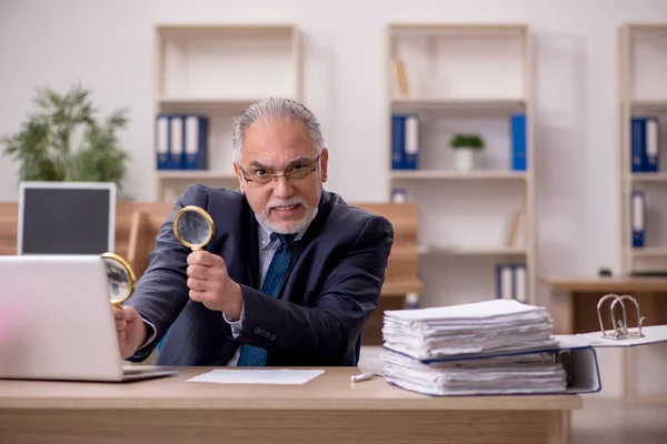 Velho empregado auditor segurando loupe no local de trabalho — Fotografia de Stock