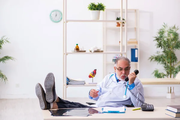 Vecchio medico di sesso maschile che parla per telefono in clinica — Foto Stock