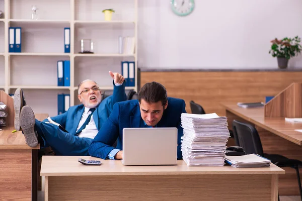 Starý muž šéf a jeho mladý muž asistent v šikaně koncept — Stock fotografie