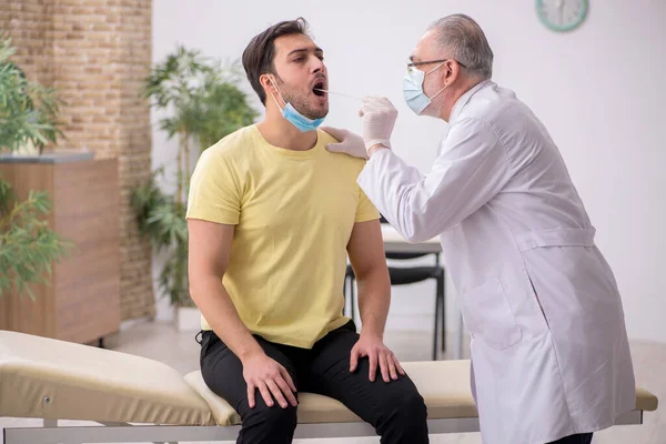 Young male patient visiting old male doctor otorhinolaryngologis — Stock Photo, Image