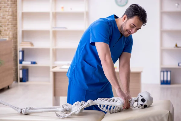 Joven médico examinando esqueleto paciente —  Fotos de Stock