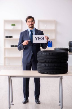 Genç adam ofiste lastik satıyor.