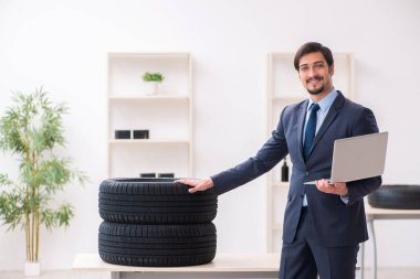 Genç adam ofiste lastik satıyor.