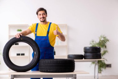 Atölyede lastiği olan genç bir erkek tamirci.