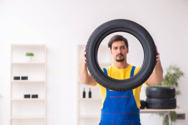 Atölyede lastiği olan genç bir erkek tamirci.