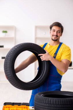Atölyede lastiği olan genç bir erkek tamirci.