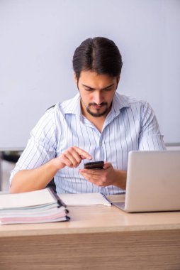 Genç erkek öğretmen beyaz tahtanın önünde.