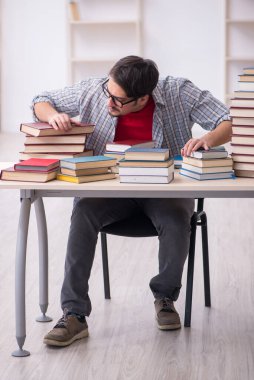 Genç bir erkek öğrenci ve sınıfta çok fazla kitap var.