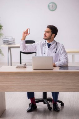 Klinikte ilaç tutan genç bir erkek doktor.