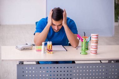 Genç dişçi hocası beyaz tahtanın önünde.