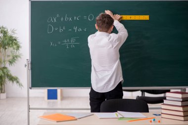 Okul çocuğu tahtanın önünde geometri okuyor.