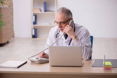 Klinikte çalışan yaşlı erkek doktor.