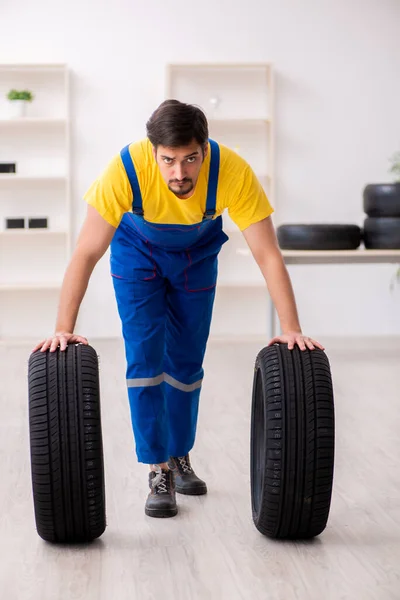 Joven trabajador de garaje con neumático en el taller —  Fotos de Stock