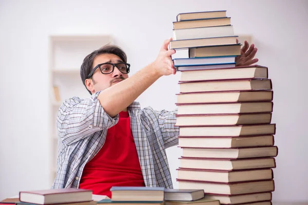 Young male student and too many books in the classroom — Stock Photo, Image