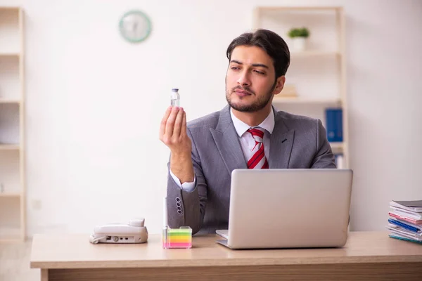 Mladý podnikatel zaměstnanec drží lahvičku v kanceláři — Stock fotografie