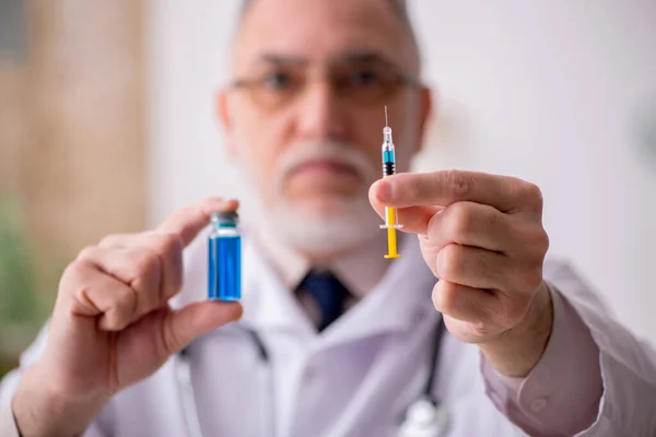 Gammel mandlig læge i vaccinationskoncept - Stock-foto