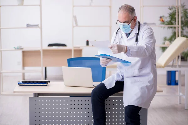 Klinikte çalışan yaşlı erkek doktor. — Stok fotoğraf