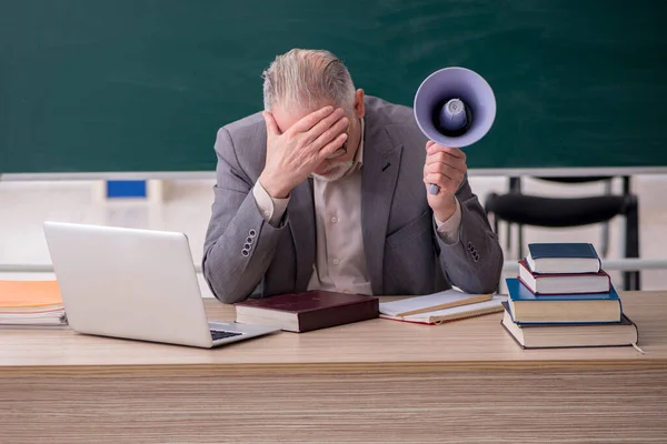 Oude mannelijke leraar met megafoon voor schoolbord — Stockfoto