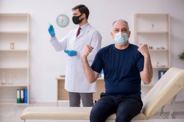 Yaşlı bir erkek hasta aşıyla genç bir doktoru ziyaret ediyor.