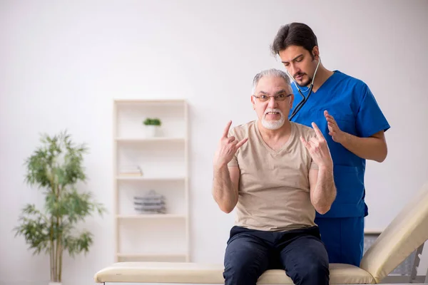 Vecchio paziente maschio visting giovane medico maschio — Foto Stock