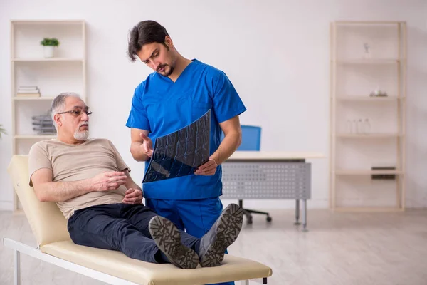 Anciano paciente masculino que mira al joven médico radilogista —  Fotos de Stock