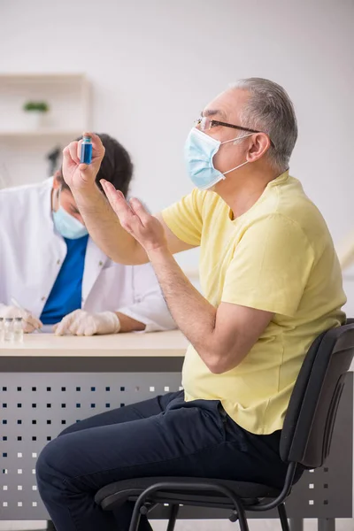 Yaşlı erkek hasta aşılama bölümünde genç bir erkek doktor. — Stok fotoğraf