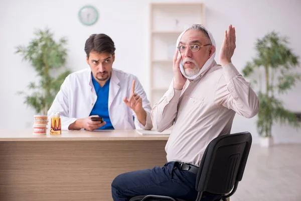 Yaşlı erkek hasta genç erkek doktor dişçiyi ziyaret ediyor. — Stok fotoğraf