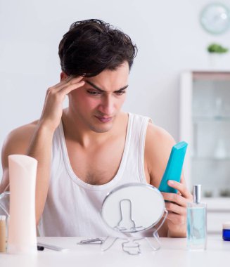 Genç yakışıklı adam aynaya bakıyor.