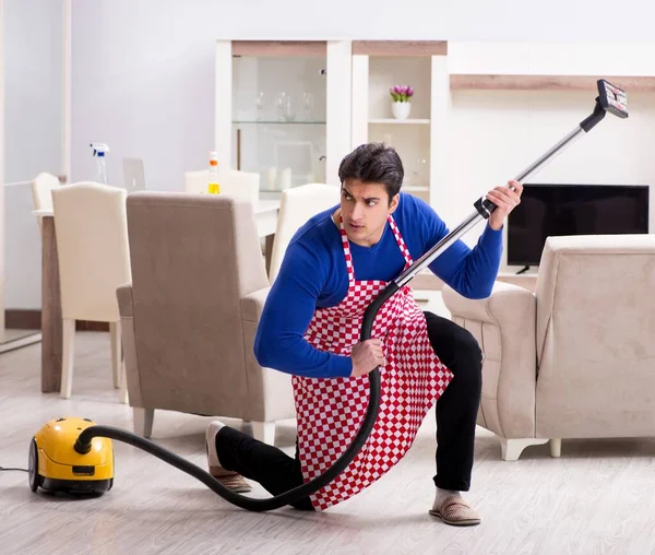 Молодий чоловік пилосос прибирає свою квартиру — стокове фото