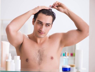 Genç adam banyoda çalışmak için hazırlanıyor.