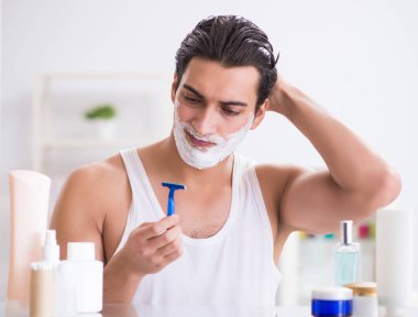 Genç yakışıklı adam sabah erkenden tıraş oluyor.