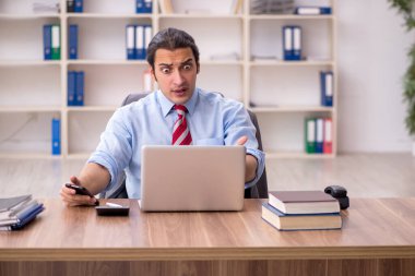 Genç erkek çalışan işyerinde oturuyor.