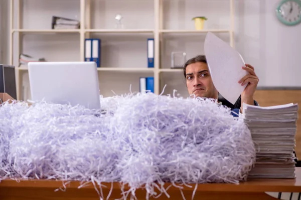 Jonge mannelijke werknemer en veel gesneden papieren in het kantoor — Stockfoto