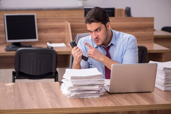 Giovane dipendente maschio infelice con un lavoro eccessivo in ufficio — Foto Stock