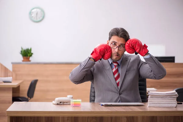 Ung man anställd bär boxningshandskar på arbetsplatsen — Stockfoto