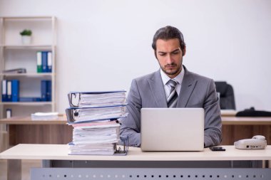 Ofisteki aşırı işten memnun olmayan genç bir erkek işçi.