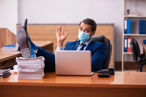 Jovem funcionário do sexo masculino que trabalha no escritório usando máscara — Fotografia de Stock
